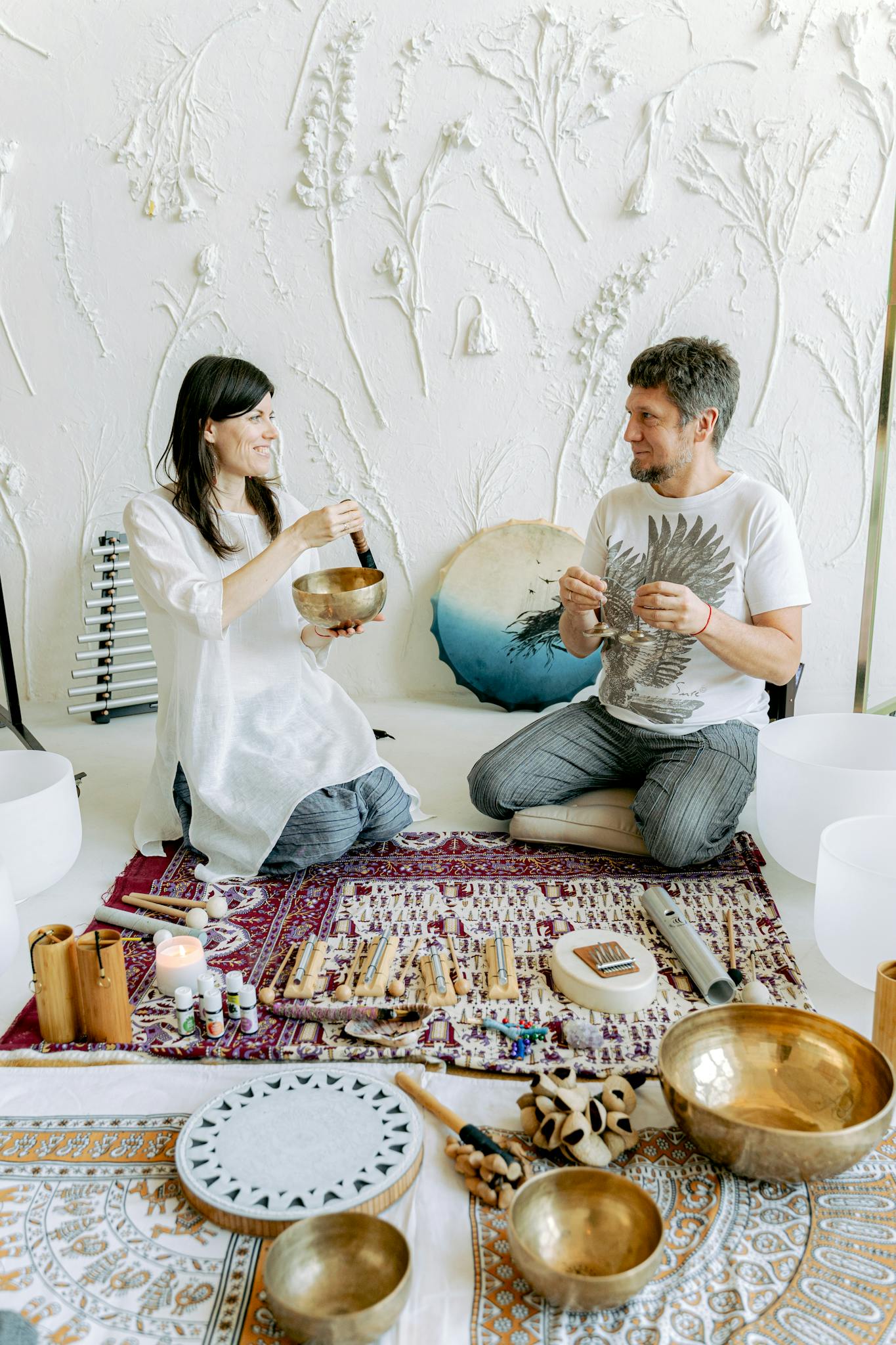 A couple engaging in sound therapy with Tibetan singing bowls indoors.