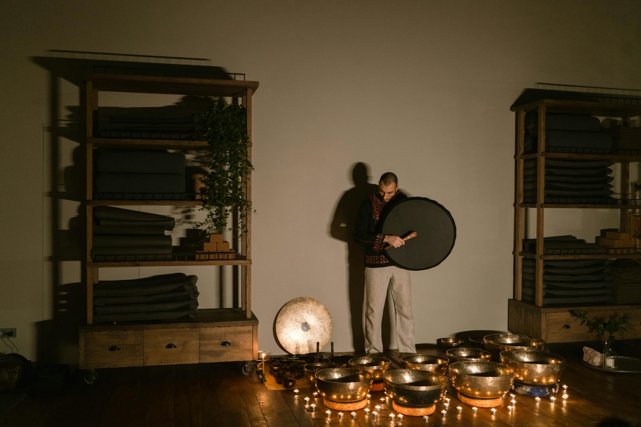 A man playing Tibetan singing bowls indoors, creating a soothing atmosphere.